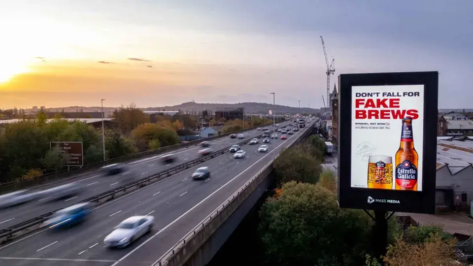 Digital roadside billboard beside a multi-lane highway at dusk